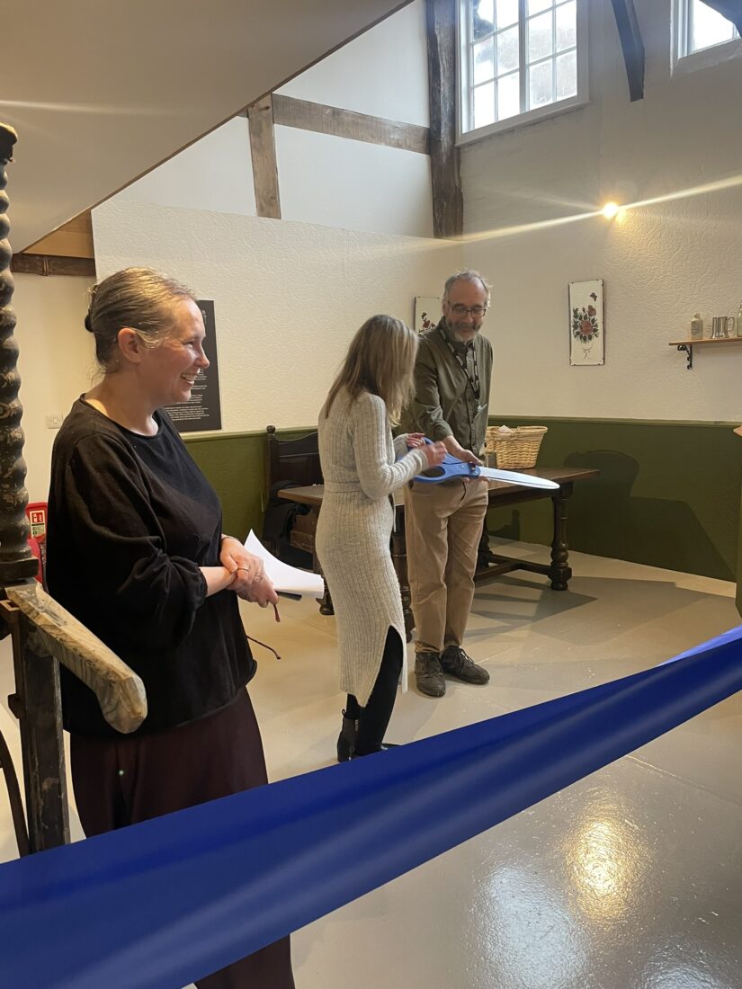 Councillor Mel Allcott holding a large pair of scissors with two people watching